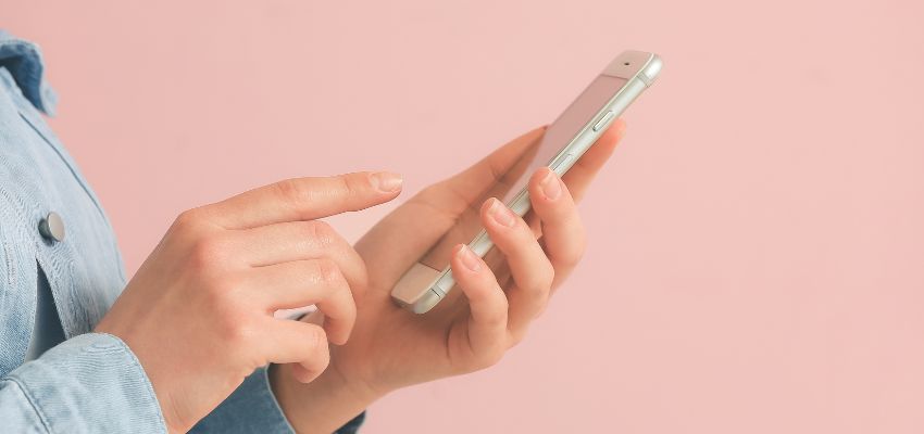 Vista ravvicinata di una persona con in mano un telefono cellulare che utilizza un'applicazione di firma mobile-friendly.