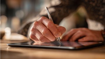 Professionista d'affari che firma un documento su una tavoletta che illustra un significato debitamente firmato