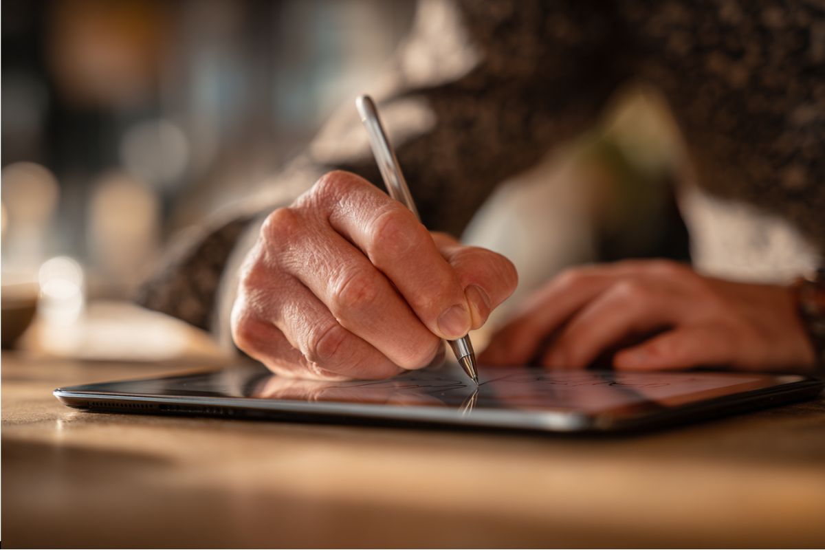 Profesional de los negocios firmando un documento en una tableta que ilustra el significado de debidamente firmado