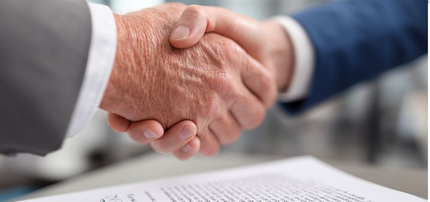 The two businessmen are shaking hands as a sign of a contract deal.