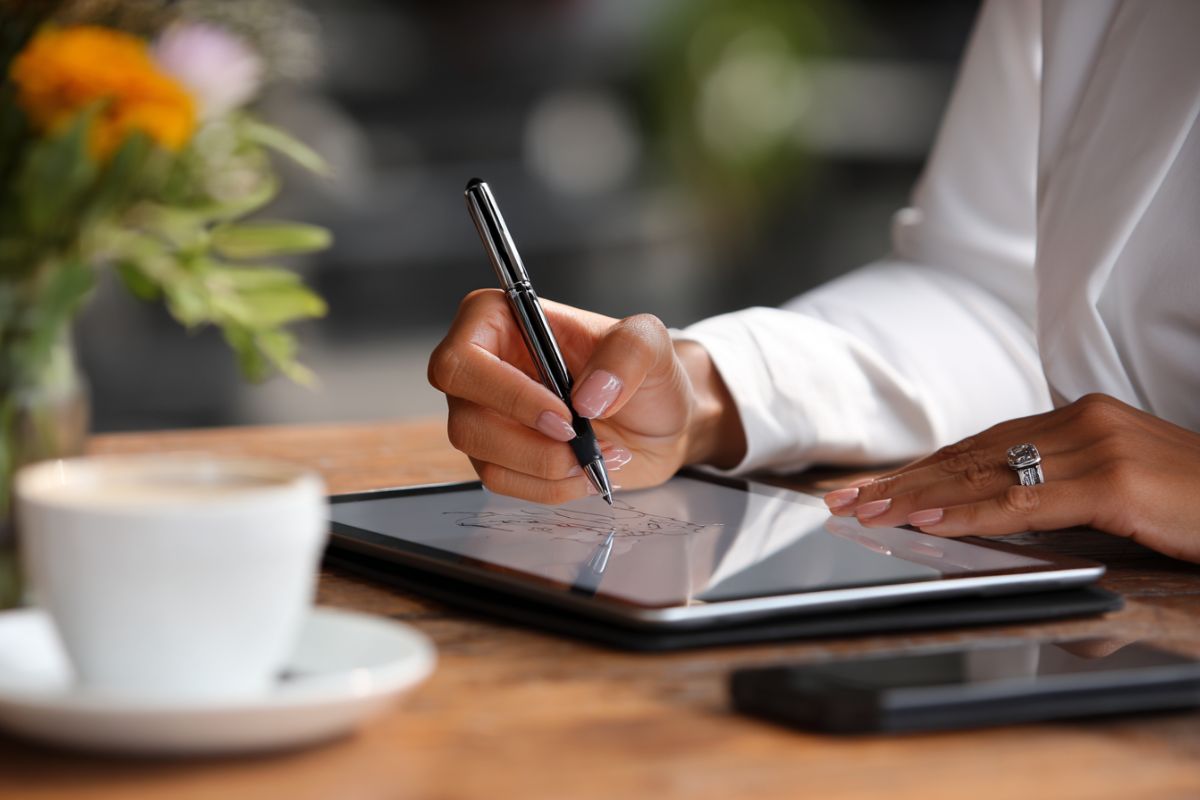 Primer plano de una persona firmando electrónicamente un documento en una tableta mediante soluciones de contratos sin papel.